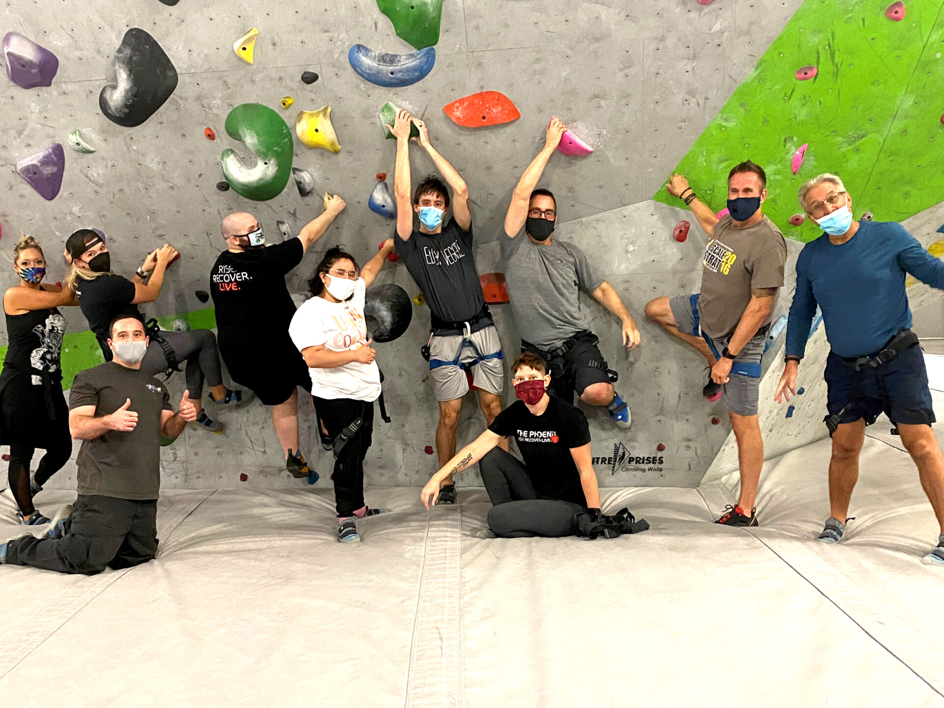Group of people masked underneath a bouldering wall