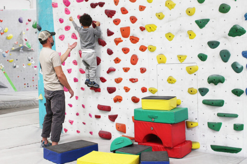 caregiver supporting toddler on the climbing wall